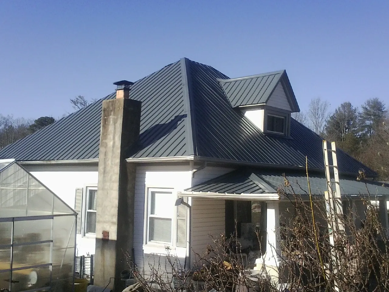 Dark blue standing seam metal roof on a white farmhouse with dormer — Slate & Tile Roof Repair by Roofing Brothers in Buckhannon