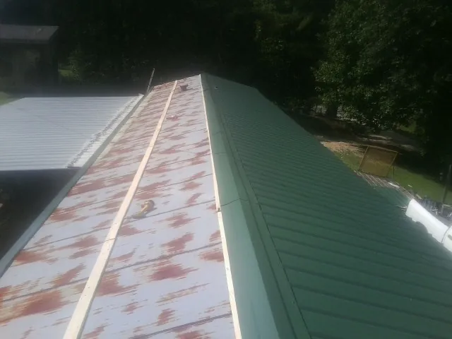 Old rusted panels beside newly installed green metal roofing — Wind Damage Roof Repair by Roofing Brothers in Buckhannon