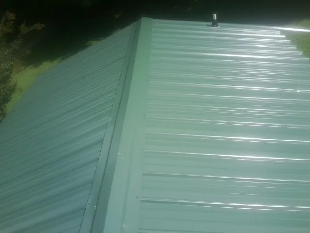New green metal panels meeting at the ridge of a roof — Flat Roof Repair work by our crew in Buckhannon