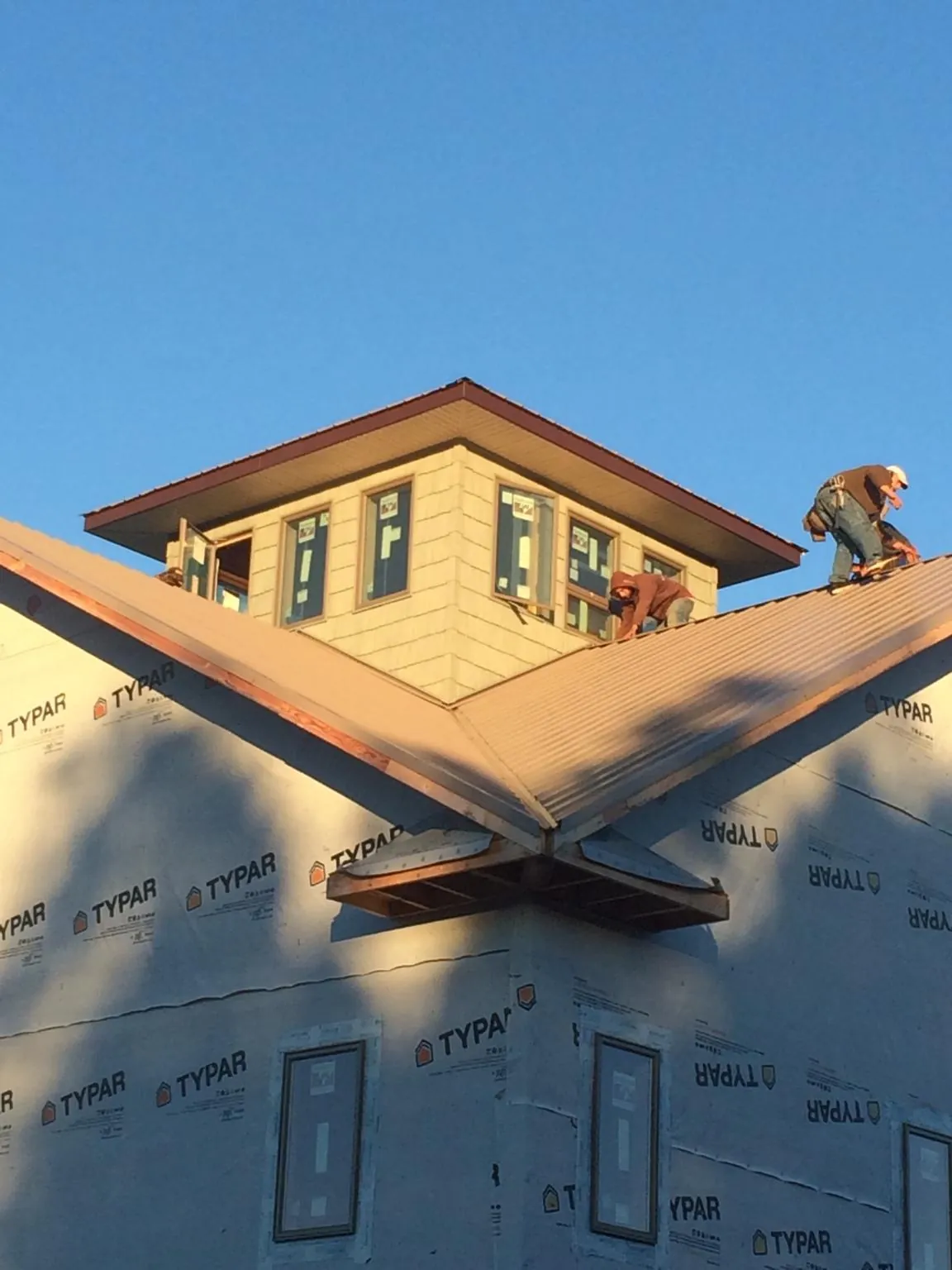 Roofers working around a rooftop cupola on a new metal roof at sunset — Roof Waterproofing in Buckhannon by Roofing Brothers